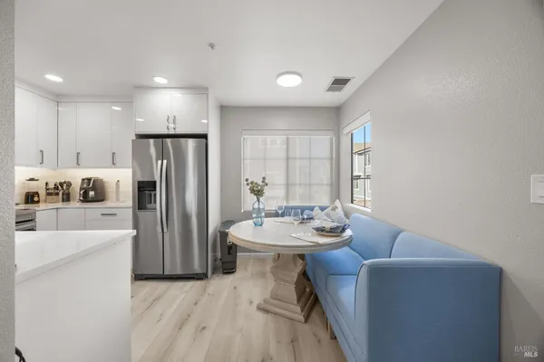 a dining room with furniture a large window and stainless steel appliances