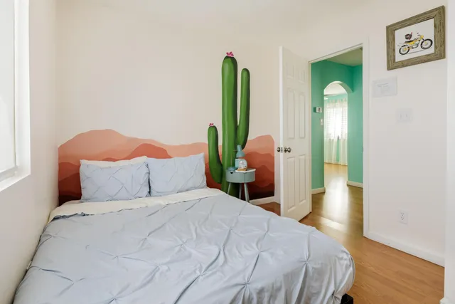 a bedroom with a bed and a dresser with wooden floor