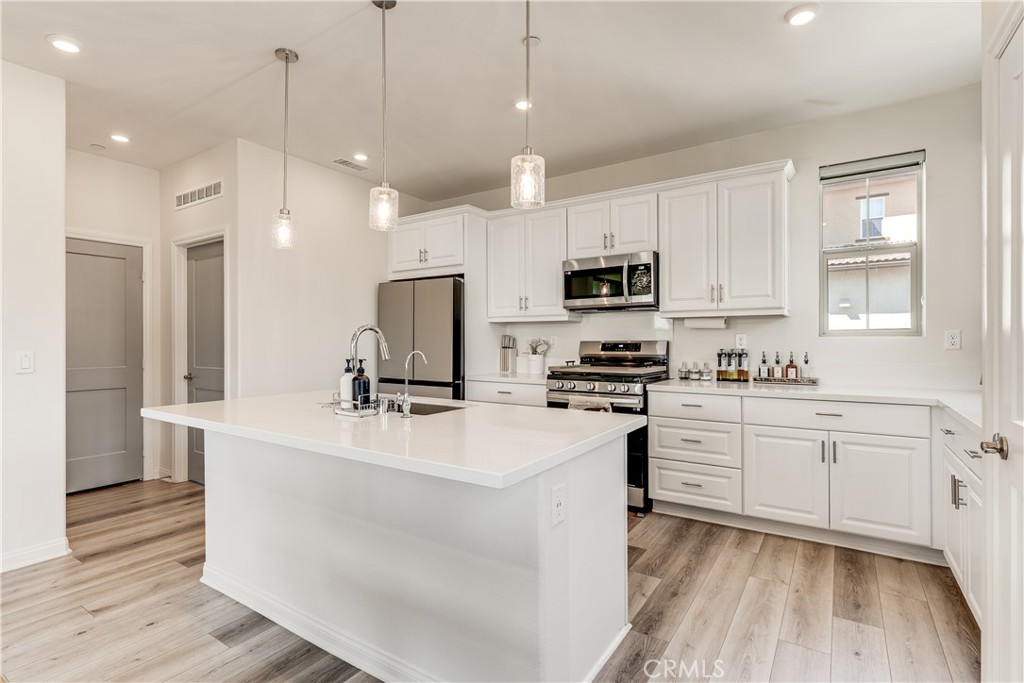 1648 Fig Tree Way Oceanside, CA 92056 - Photo 9 of 45 a kitchen with kitchen island white cabinets and stainless steel appliances