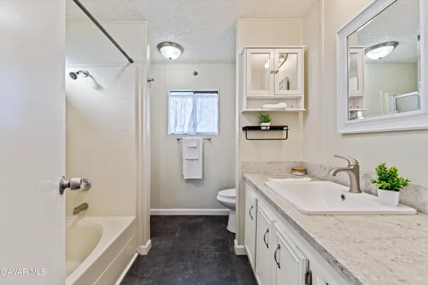 a bathroom with a granite countertop sink a toilet a bathtub and shower