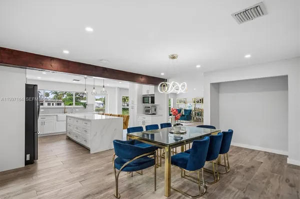 a kitchen with a dining table chairs and wooden floor