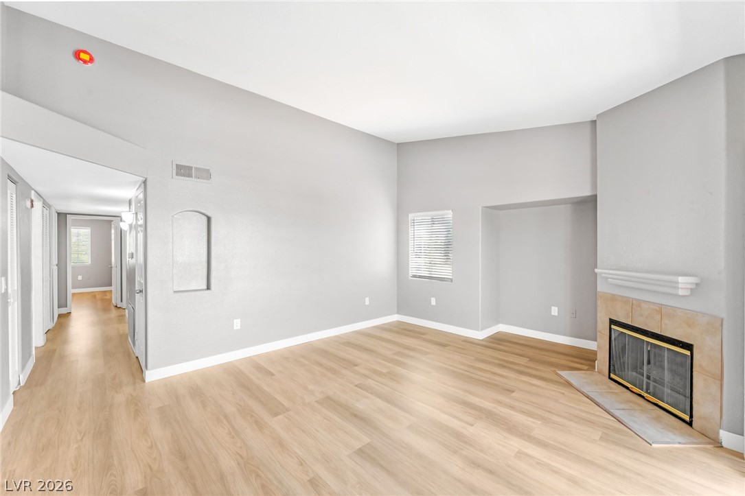 3318 North Decatur Boulevard, Unit 2152 Las Vegas, NV 89130 - Photo 7 of 58 A spacious living area features a charming fireplace with a tiled hearth and light wood flooring.