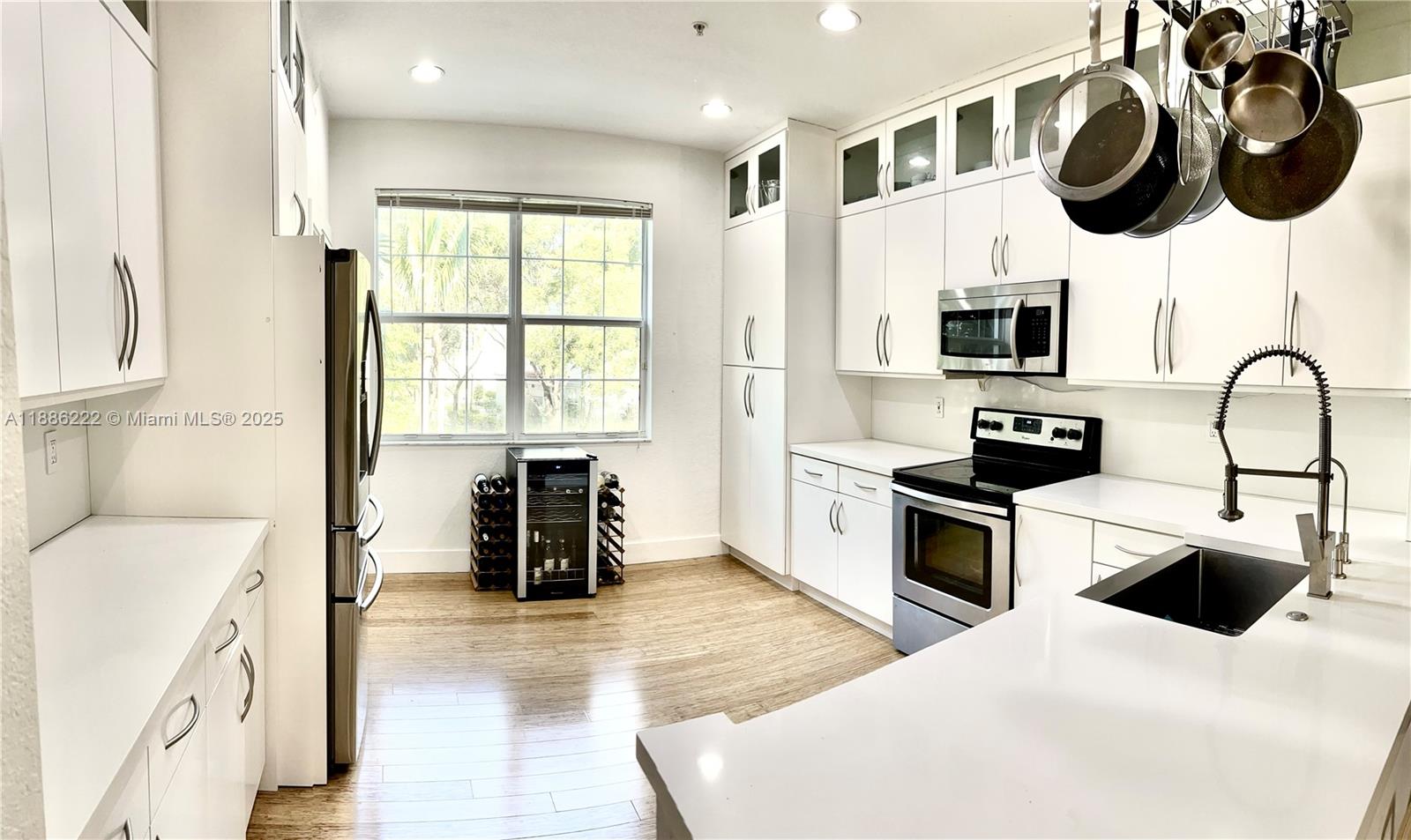 2549 Southwest 118th Way, Unit 302 Miramar, FL 33025 - Photo 2 of 43 a kitchen with stainless steel appliances granite countertop a stove a sink dishwasher and a microwave with wooden floor