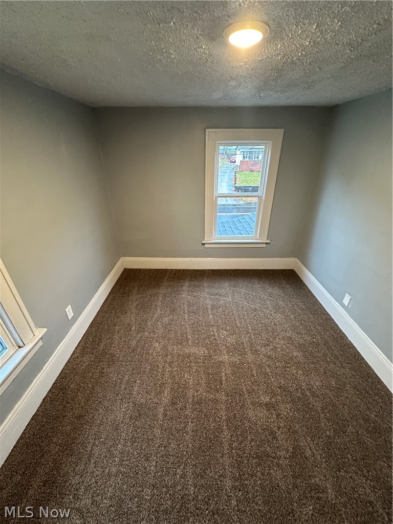 1655 Manchester Road Akron, OH 44314 - Photo 3 of 5 Empty room featuring dark colored carpet and a textured ceiling