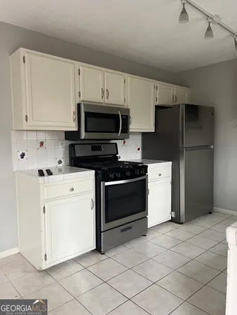 a kitchen with white cabinets and stainless steel appliances