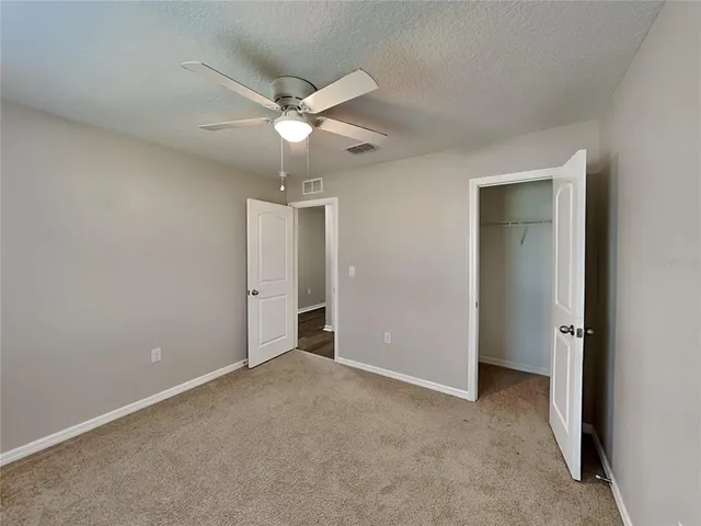 an empty room with closet and a ceiling fan