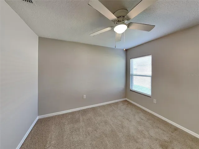 an empty room with windows and fan
