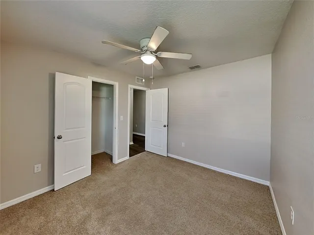 an empty room with closet and a ceiling fan