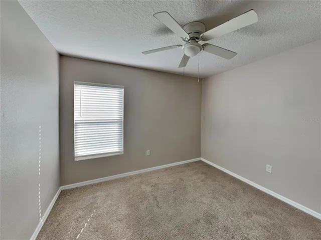 an empty room with a window and a fan
