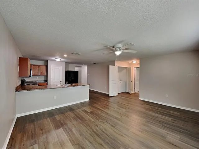 a view of kitchen and empty room with wooden floor