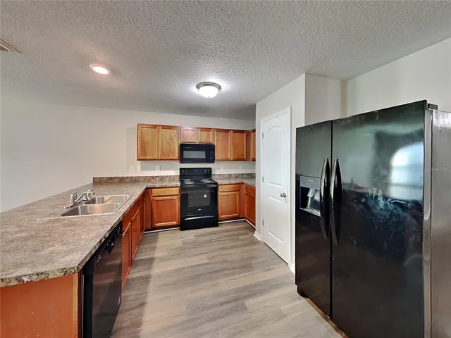 a kitchen with stainless steel appliances granite countertop a refrigerator a sink and a stove