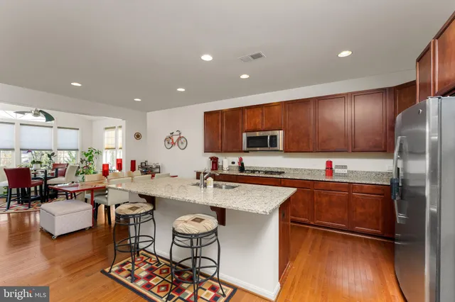 a kitchen with stainless steel appliances granite countertop a refrigerator a stove top oven a sink dishwasher and dining table with wooden floor