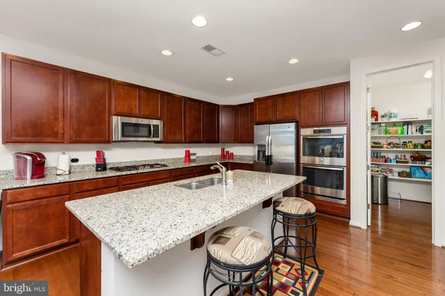 a kitchen with stainless steel appliances granite countertop a stove top oven a sink dishwasher a dining table and chairs with wooden floor