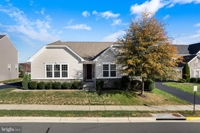 a view of a white house next to a yard and road