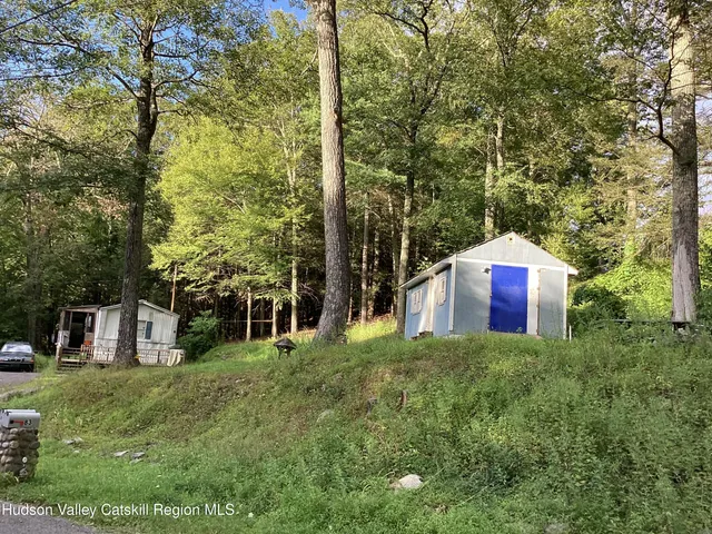 a view of a house with a yard and large trees