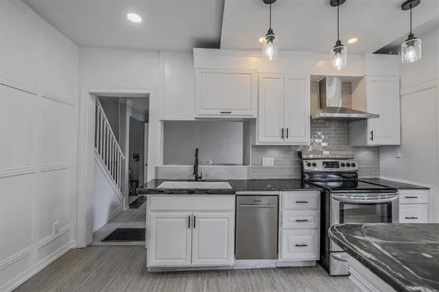 a kitchen with stainless steel appliances granite countertop a sink stove a refrigerator and white cabinets with wooden floor