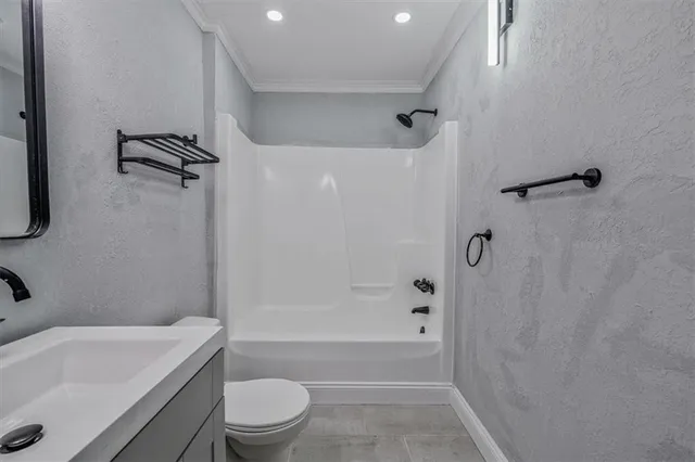 a bathroom with a granite countertop bathtub shower sink vanity and toilet