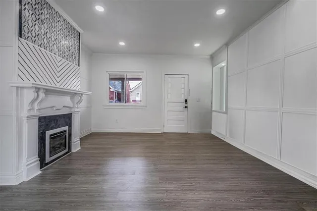 a view of an empty room with wooden floor fireplace and a window