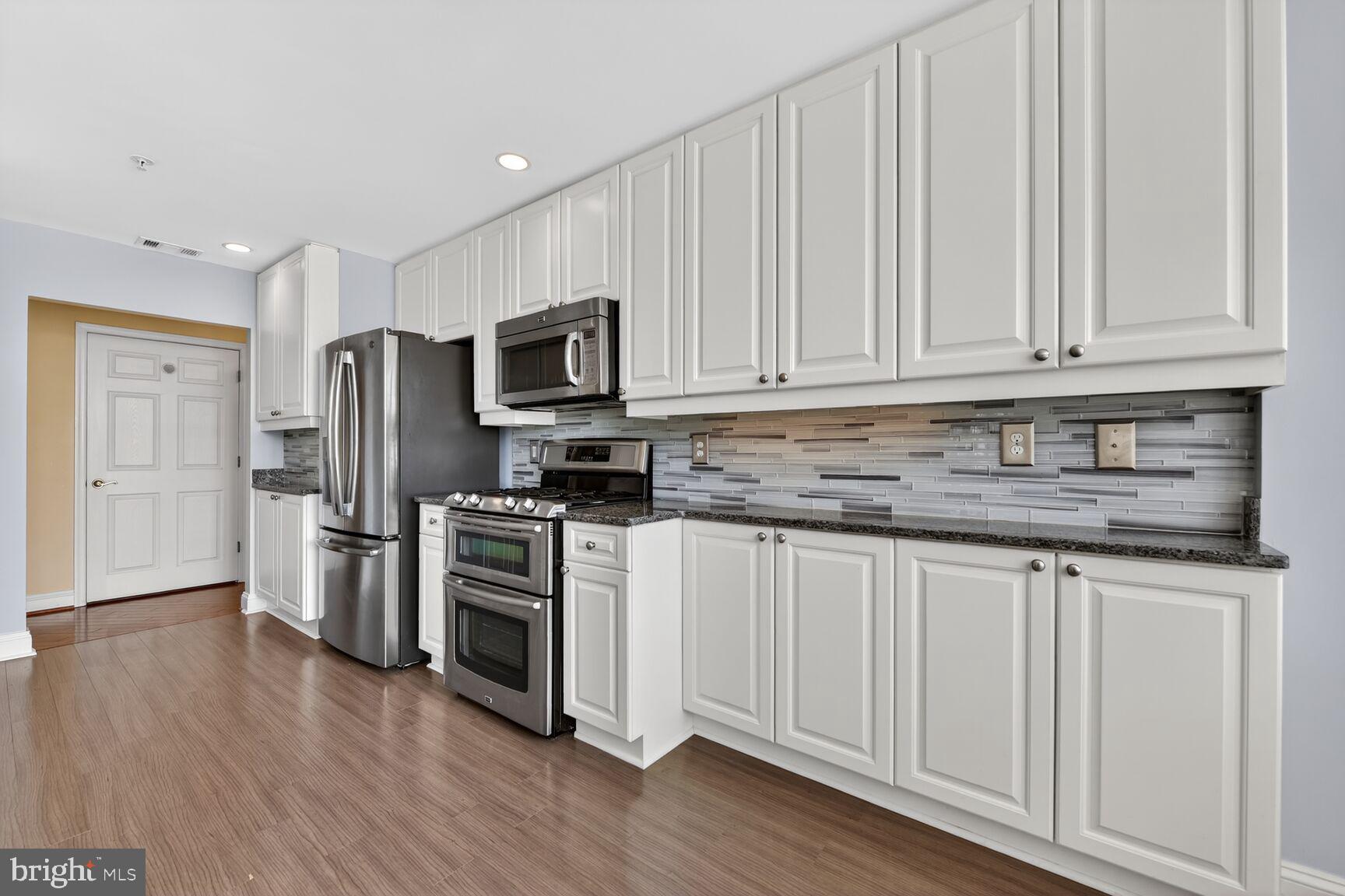 11776 Stratford House Place, Unit 502 Reston, VA 20190 - Photo 11 of 35 a kitchen with granite countertop white cabinets stainless steel appliances and wooden floor