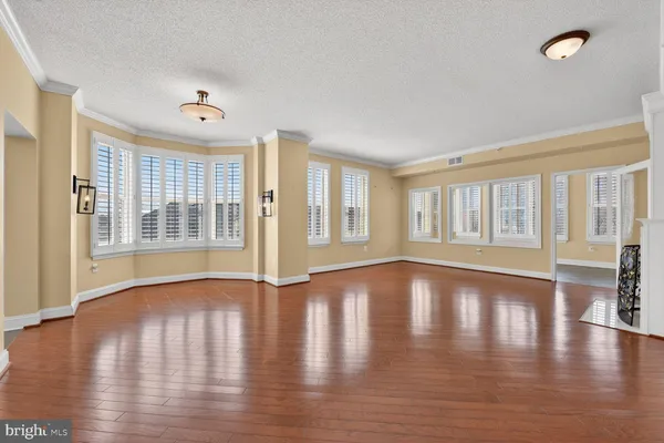 an empty room with wooden floor fireplace and windows