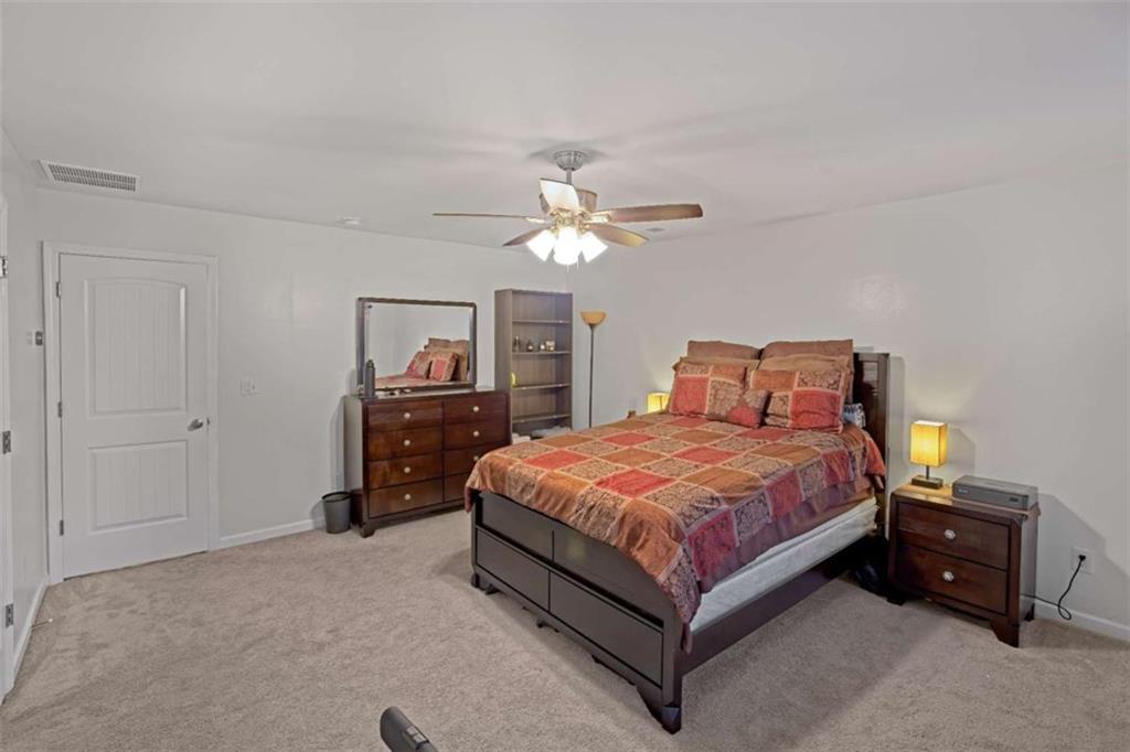 12001 Guelph Circle Hampton, GA 30228 - Photo 15 of 31 a bedroom with a bed and a chandelier