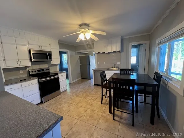 a kitchen with stainless steel appliances granite countertop a stove a sink a microwave a dining table and chairs