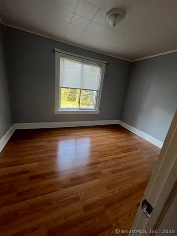 a view of empty room with window and wooden floor