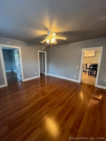 a view of an empty room with window and wooden floor