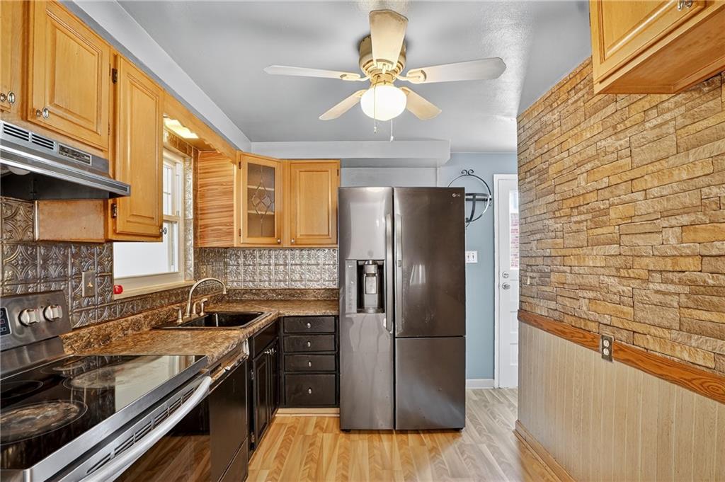 1209 Varner Road Pittsburgh, PA 15227 - Photo 11 of 40 a kitchen with stainless steel appliances granite countertop a refrigerator a sink dishwasher a stove and white countertops with wooden floor