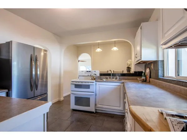 a kitchen with stainless steel appliances granite countertop a refrigerator a stove and a sink with large countertops