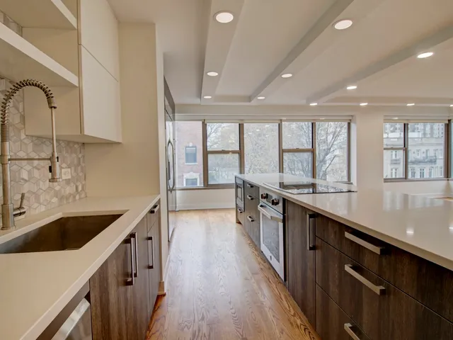 a kitchen with stainless steel appliances a sink stove and wooden floor