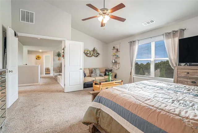 a spacious bedroom with a bed and a flat screen tv