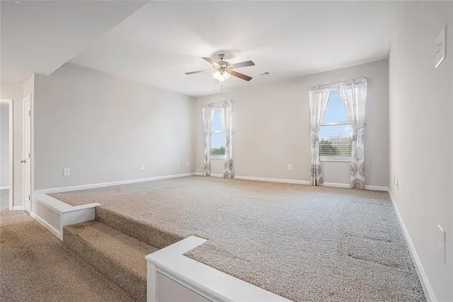 a view of an empty room with window and chandelier fan