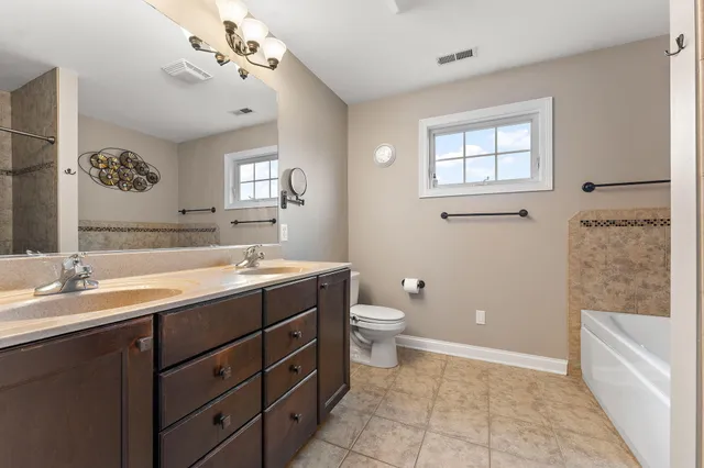 a spacious bathroom with a granite countertop sink a toilet mirror and bathtub