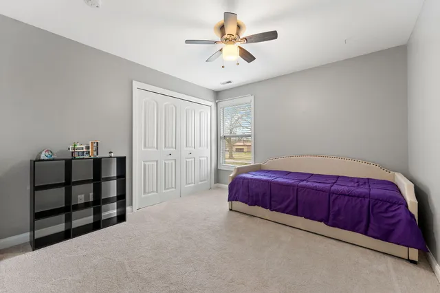 a spacious bedroom with a bed and a chandelier fan