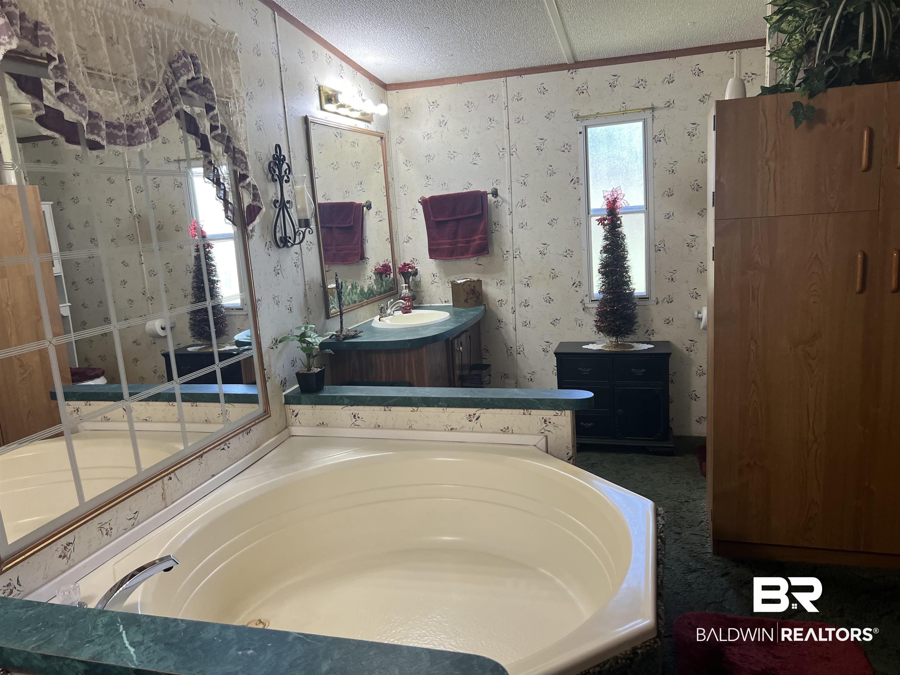 1177 McMillan Road Monroeville, AL 36460 - Photo 15 of 21 Full bath with wallpapered walls, crown molding, a bath, vanity, and a textured ceiling