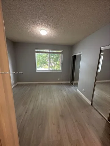 an empty room with wooden floor and window