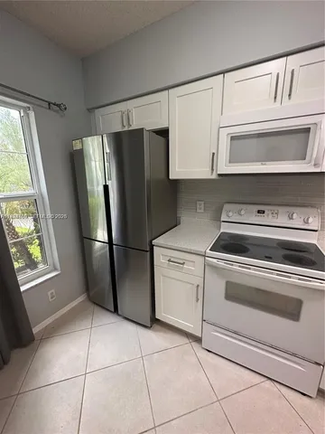 a kitchen with a refrigerator sink and cabinets