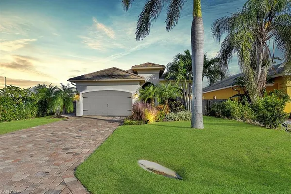 a view of a house with a yard and palm trees