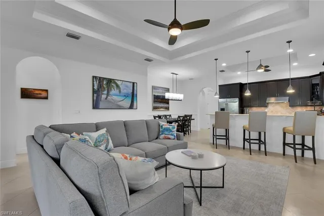 a living room with furniture kitchen view and a chandelier