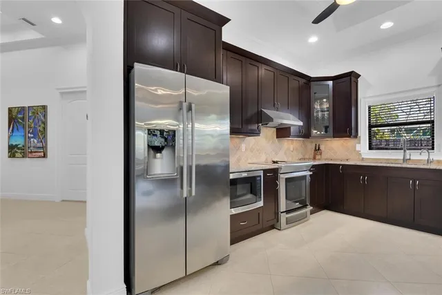 a kitchen with stainless steel appliances kitchen island granite countertop a refrigerator and a sink