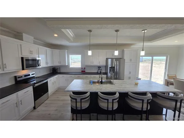 a kitchen with sink a microwave cabinets and chairs
