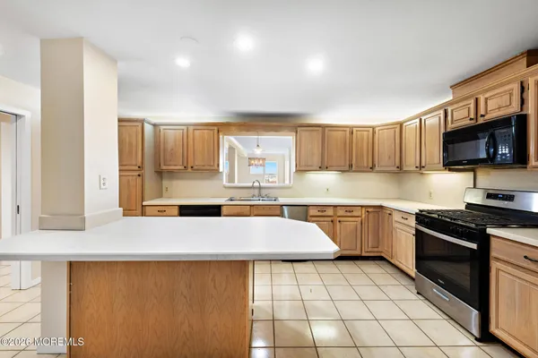 a large kitchen with stainless steel appliances a stove a sink a microwave and cabinets