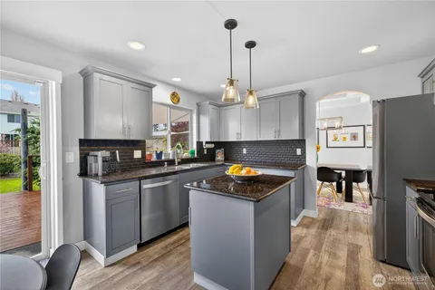 a kitchen with stainless steel appliances granite countertop a sink a stove and a refrigerator