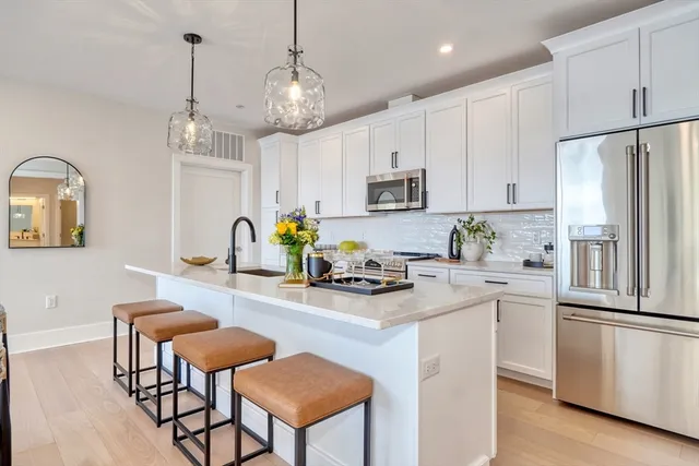 a kitchen with stainless steel appliances granite countertop a refrigerator a stove a sink dishwasher a stove a dining table and chairs with wooden floor