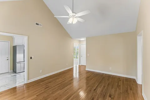 a kitchen with stainless steel appliances granite countertop a refrigerator a sink a stove and white cabinets with wooden floor