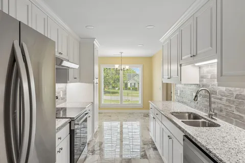a kitchen with granite countertop white cabinets and a sink