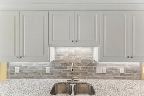 a kitchen with granite countertop a sink and white cabinets