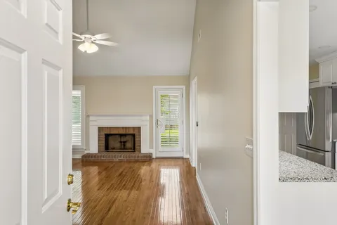 an empty room with wooden floor fireplace and windows