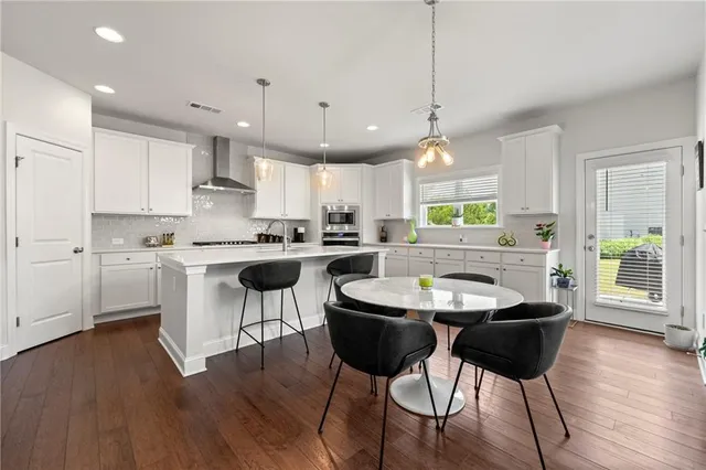 a kitchen with stainless steel appliances kitchen island granite countertop a sink a stove a dining table chairs and view living room